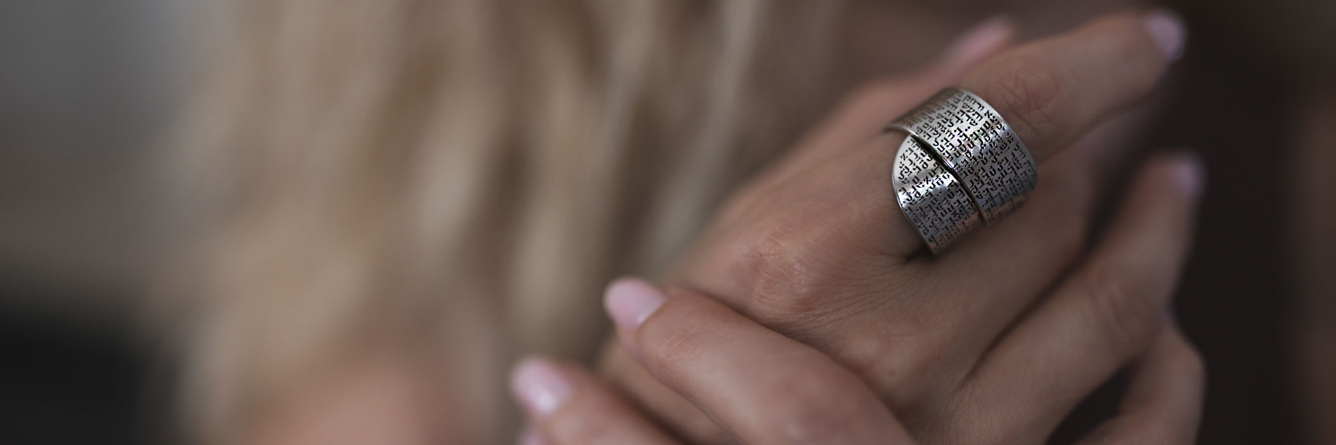 Sterling silver wide ring engraved with Hebrew text on a woman’s hand