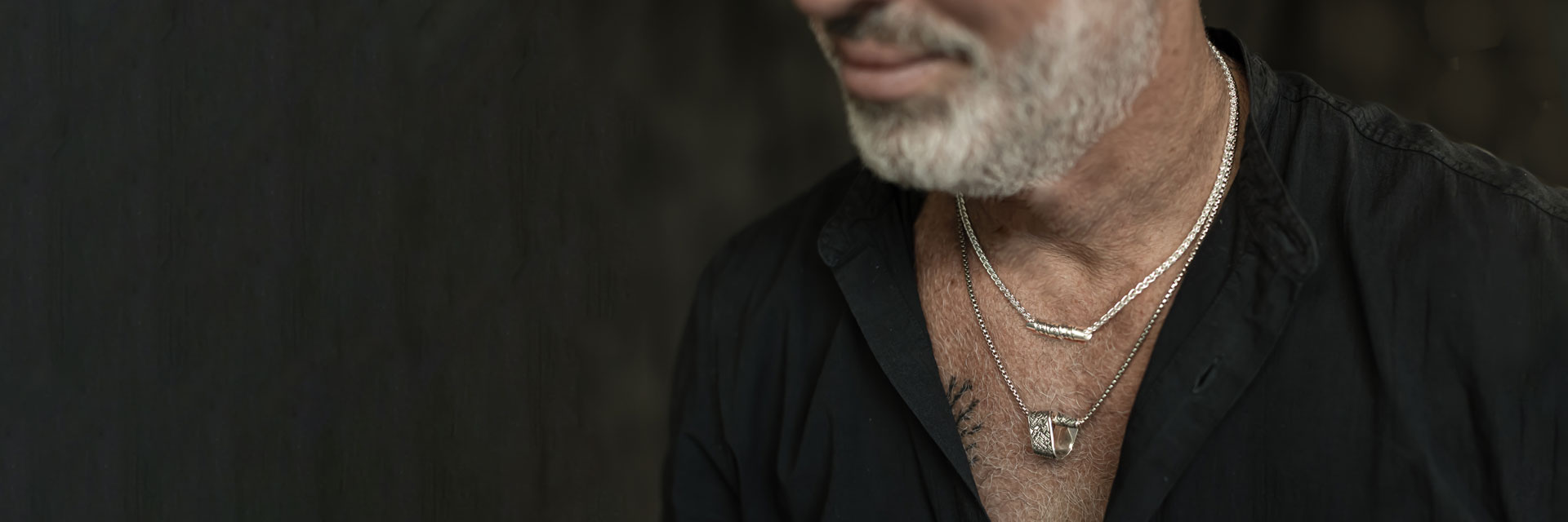 Close-up of a man wearing layered sterling silver Hebrew engraved necklaces