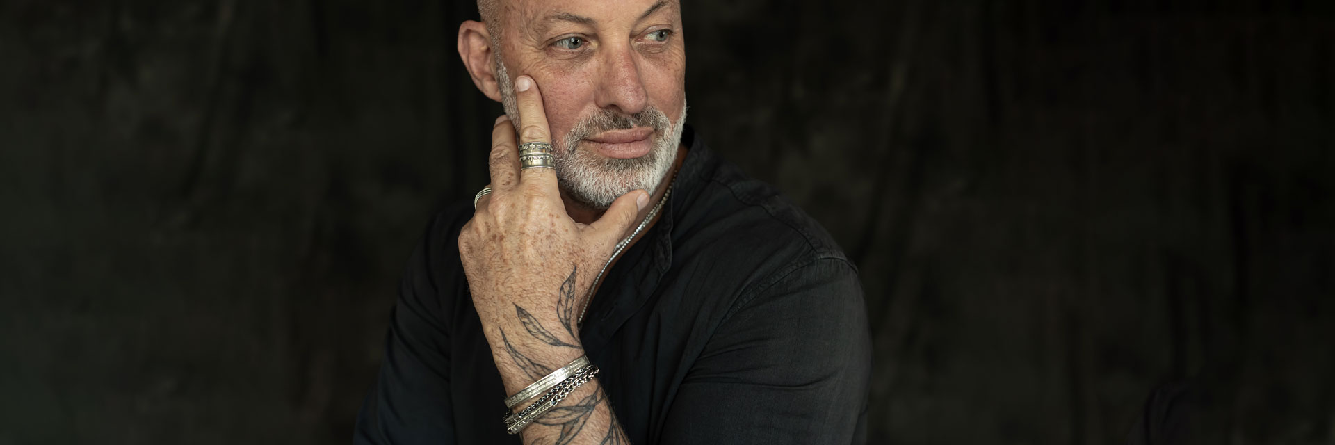 Mature man wearing multiple silver bracelets and engraved rings, showcasing Hebrew jewelry for men