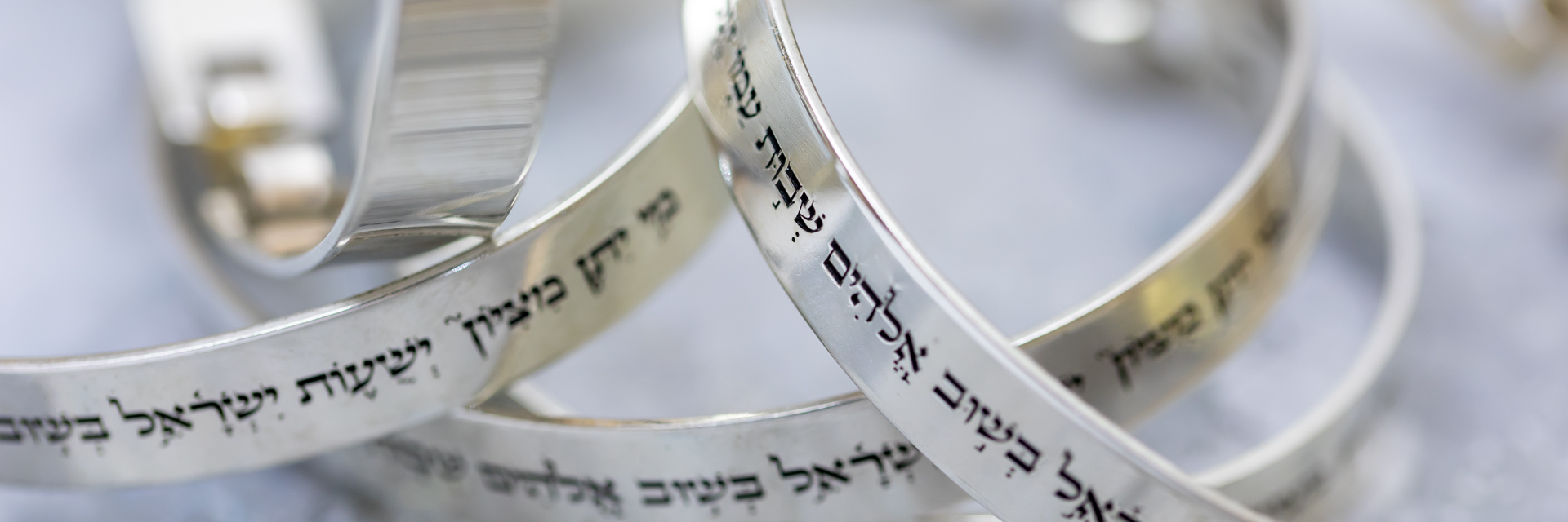 Close-up of silver bracelets engraved in Hebrew with Jewish blessings