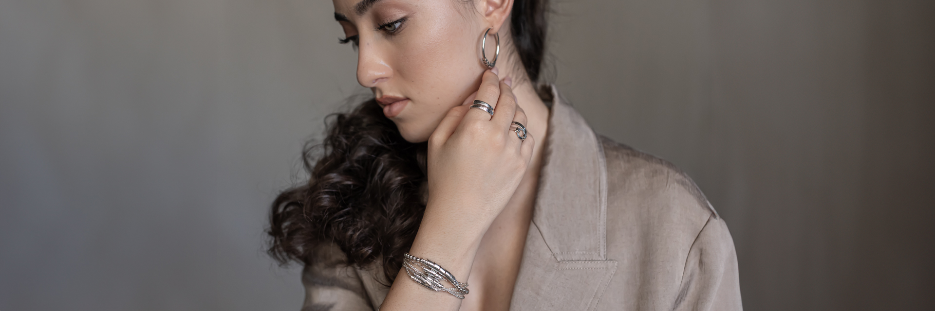 Woman wearing handmade sterling silver jewelry with Hebrew engravings – rings, bracelet, and earrings
