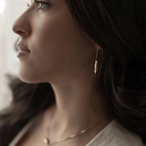 Woman wearing delicate gold Hebrew earrings and necklace