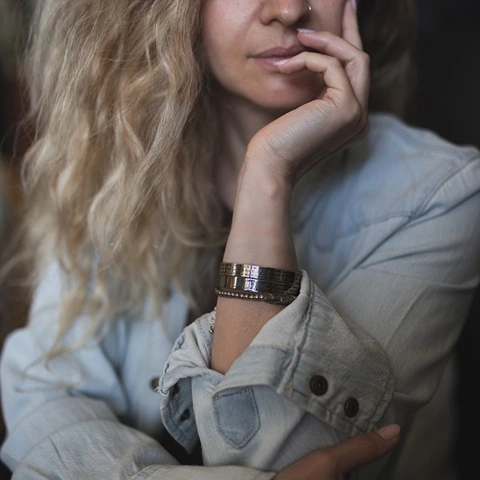 Woman wearing layered engraved gold and silver Hebrew bracelets